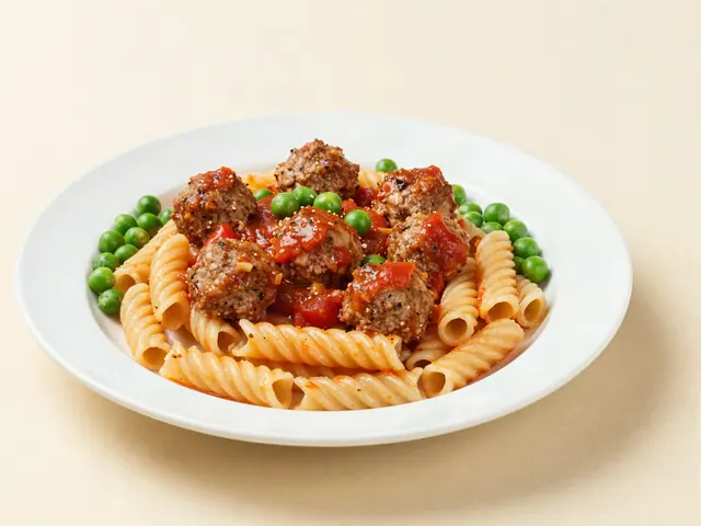 Turkey meatball pasta with a side of green peas on a plate
